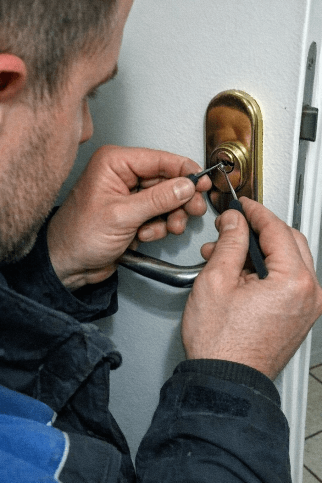Schlosstechniker mit Arbeitshandschuhen setzt einen neuen Profilzylinder in eine Wohnungstür ein